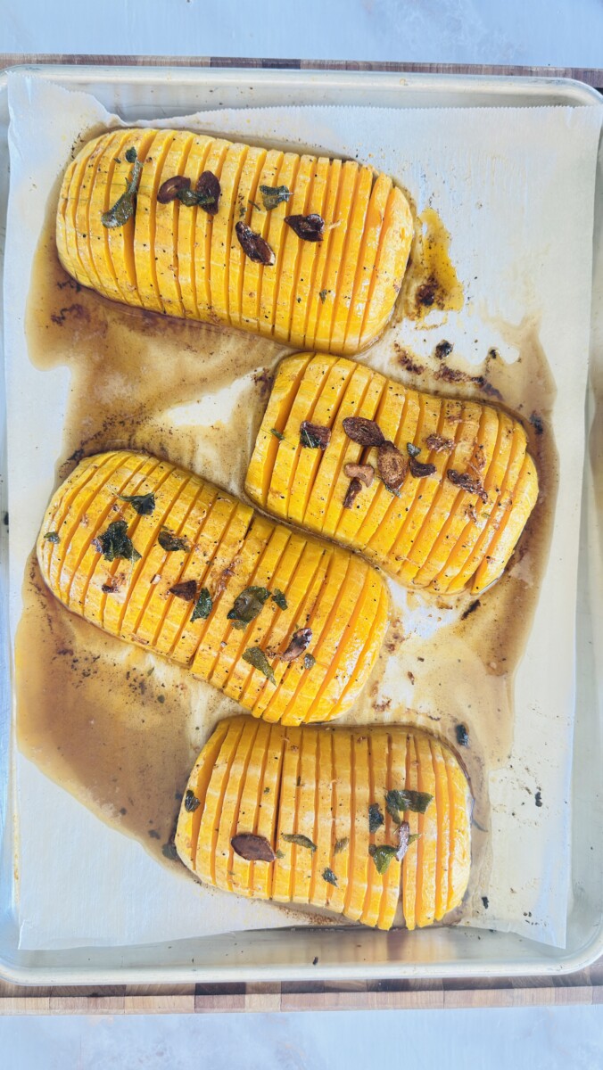 Alt Text: Sage brown butter being drizzled over hot roasted hasselback butternut squash on baking sheet