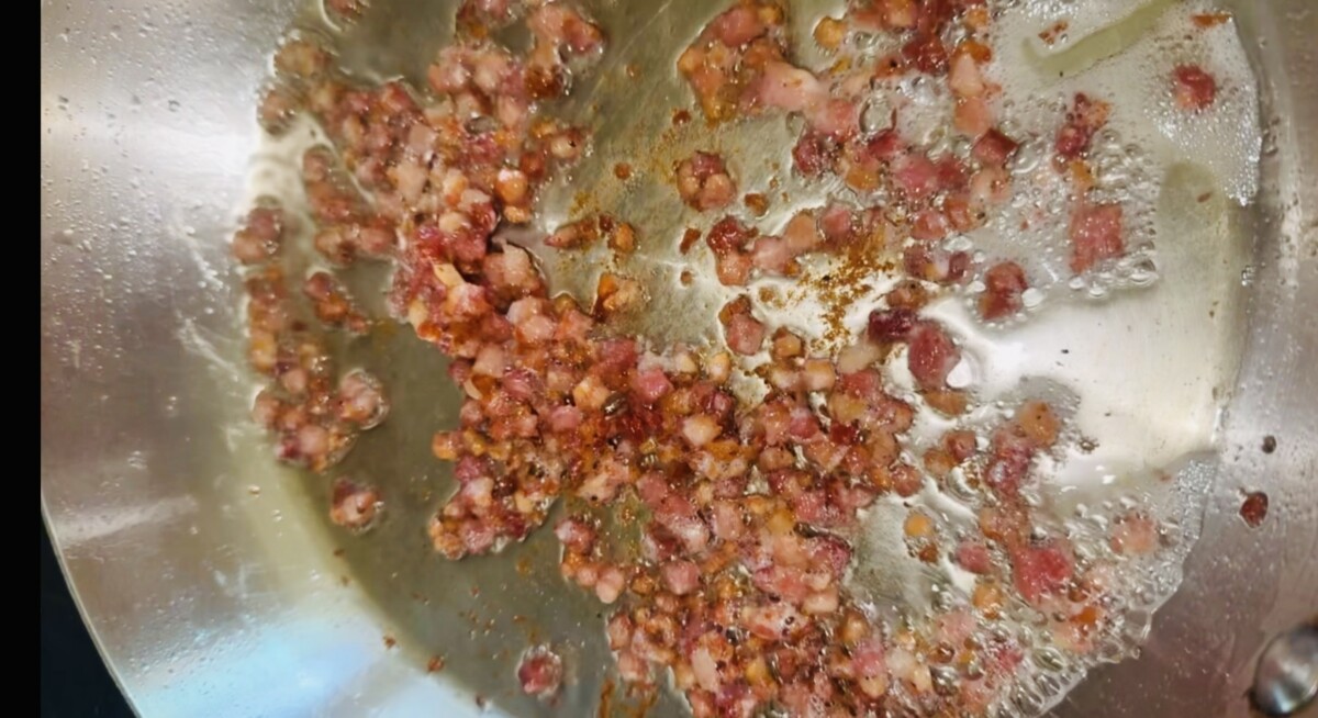 Diced pancetta cooking until crispy in a skillet