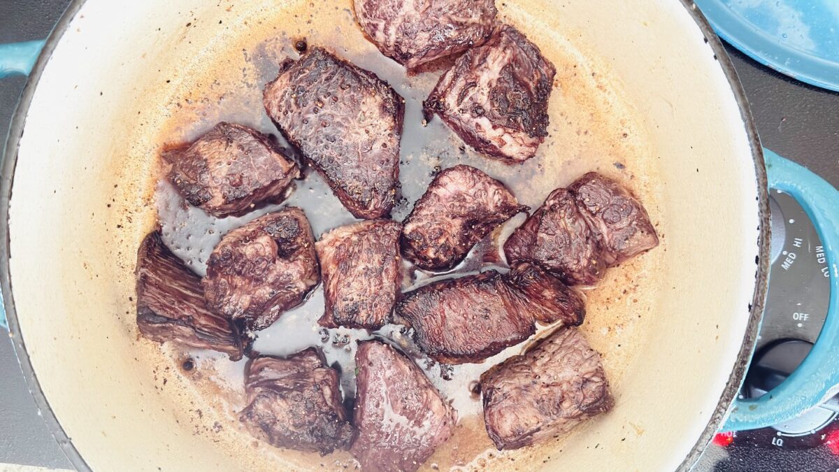 Beef cubes searing in Dutch oven with golden-brown crust for Beef Bourguignon