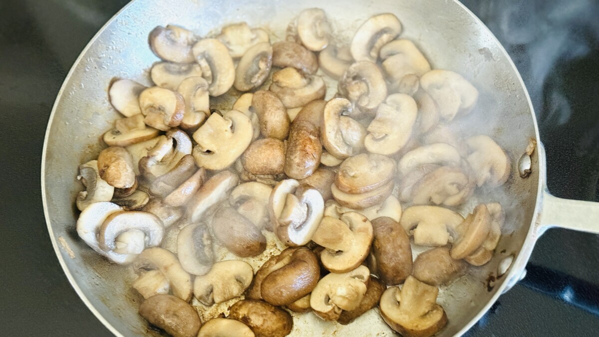 Baby bella mushrooms sautéing in butter until golden brown in a skillet