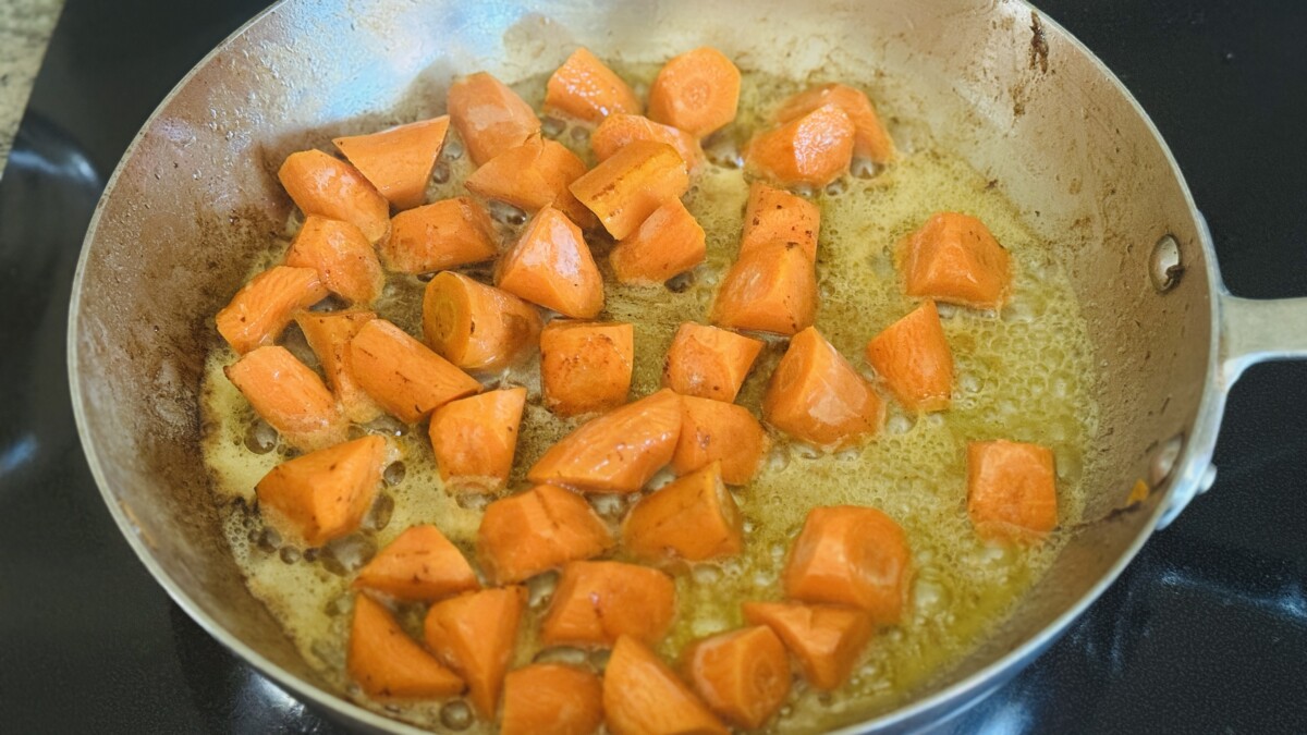 Carrot pieces sautéing in butter until tender in a skillet