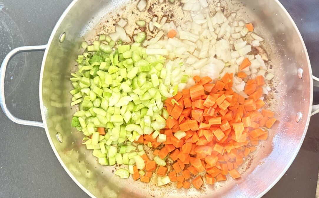 Diced onions, carrots, and celery sautéing in olive oil for chicken cacciatore soffritto base