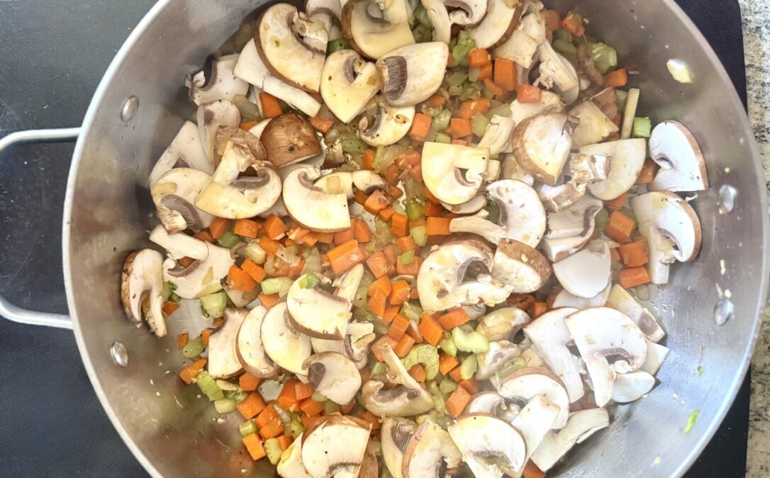 Fresh cremini and rehydrated porcini mushrooms cooking in a pot for chicken cacciatore