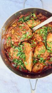 Rustic chicken cacciatore with fall-off-the-bone chicken, porcini and cremini mushrooms in red wine tomato sauce in a cast iron Dutch oven