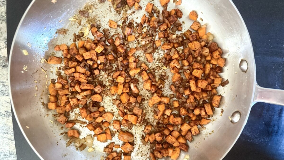 Shallots, diced carrots, and garlic sautéing in olive oil in a pan for pearl couscous recipe