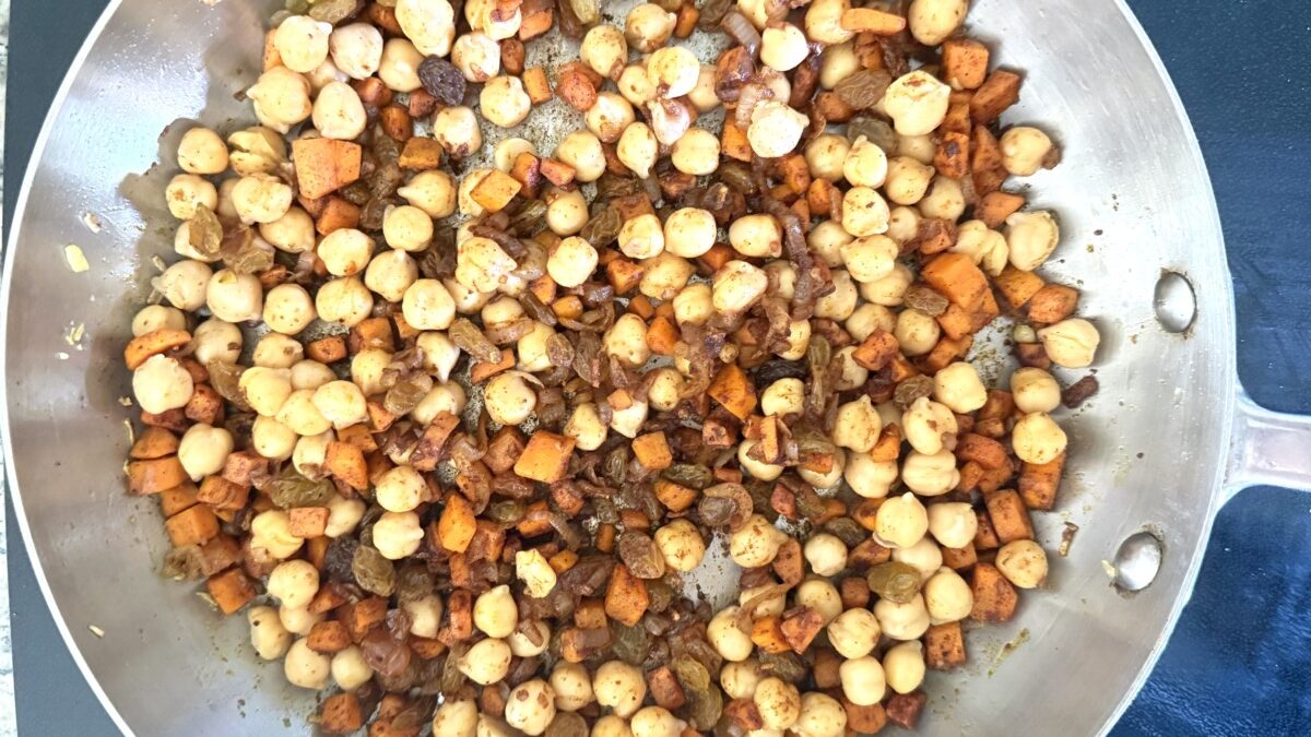 Chickpeas being added to sautéed vegetables and spices in pan for pearl couscous recipe