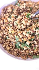 Pearl couscous recipe with chickpeas, carrots, golden raisins, and toasted pine nuts garnished with fresh herbs