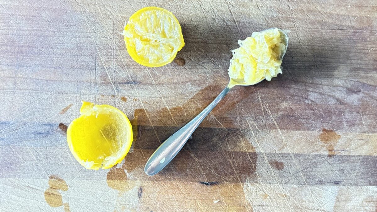 Scooping out the pulp from a preserved lemon, keeping only the skin for harissa roasted carrots