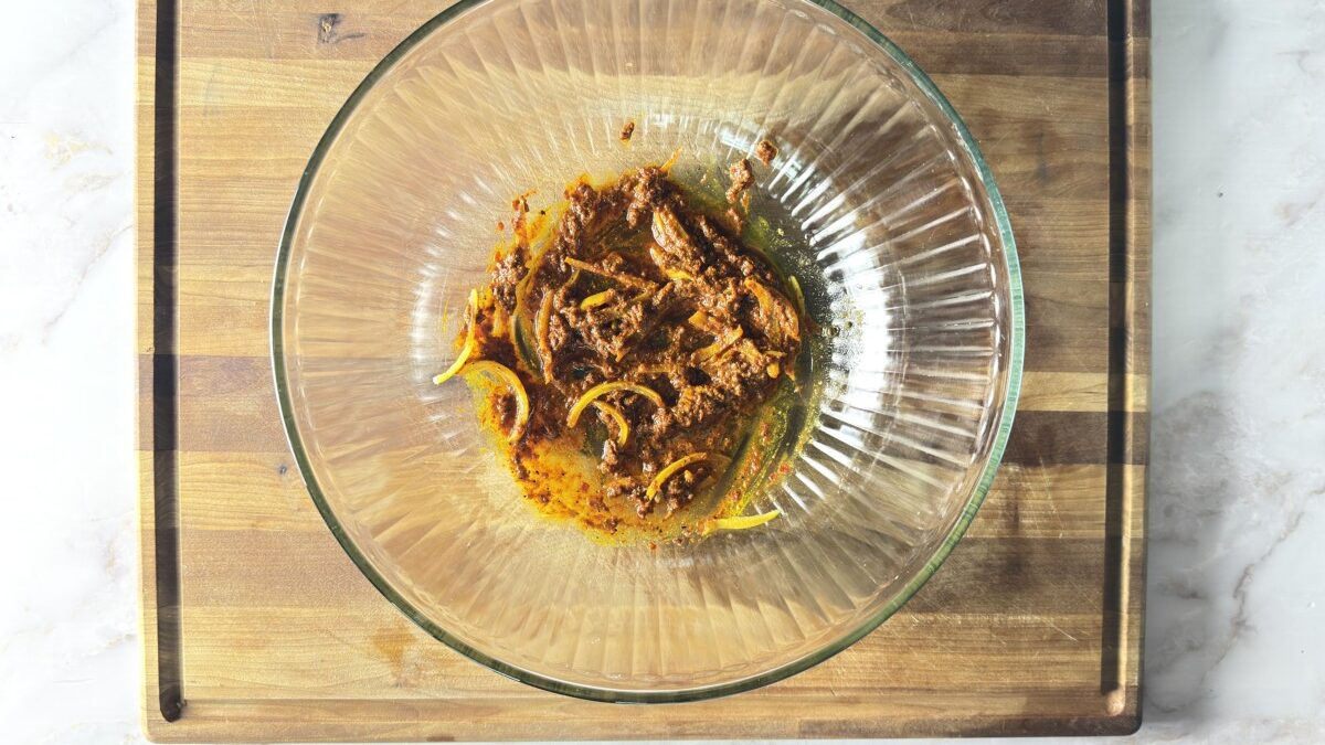 Harissa paste mixed with olive oil, cumin, turmeric, ginger, and preserved lemon ribbons in a large bowl